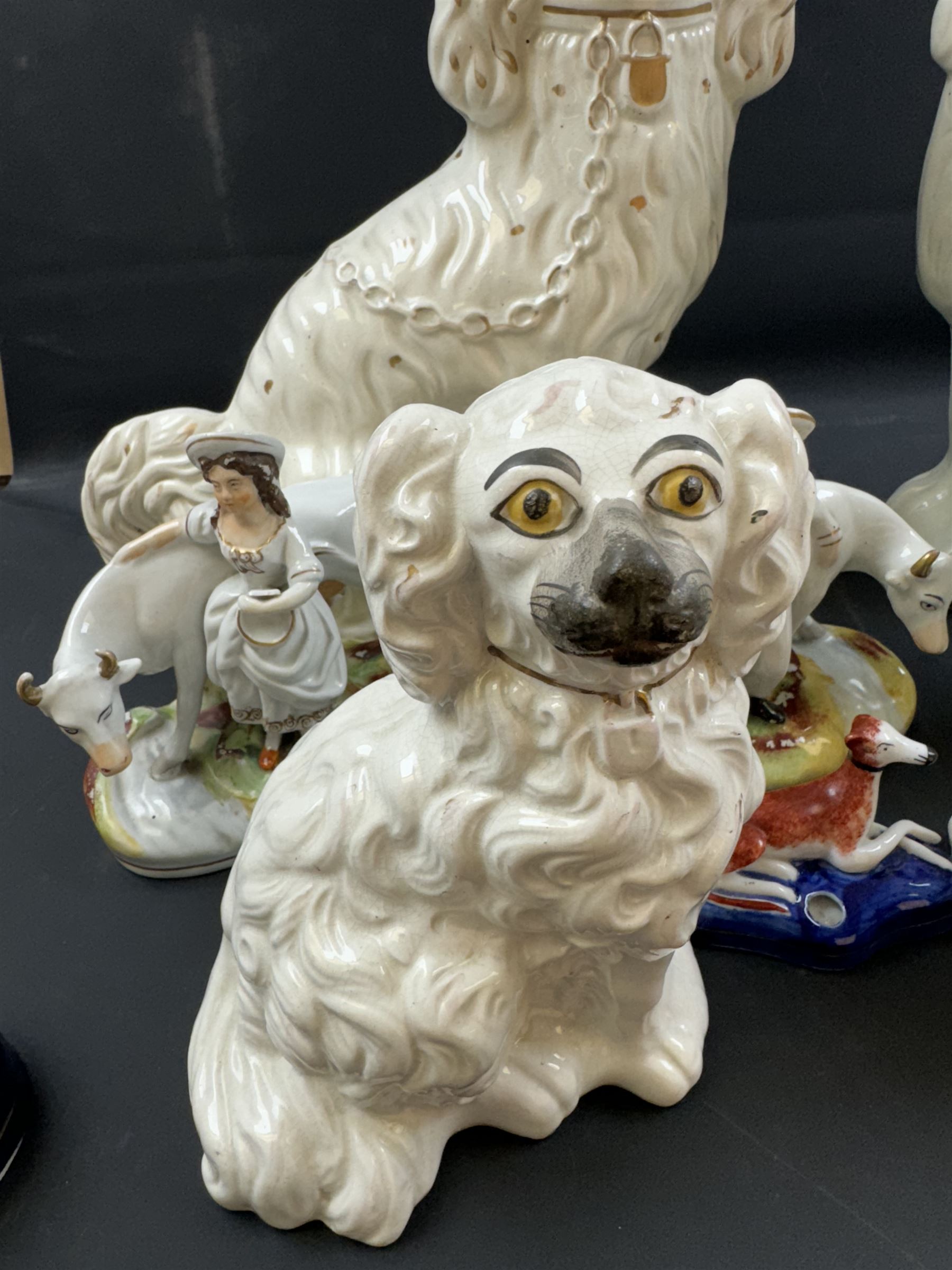 Staffordshire and Staffordshire style figures, to include a chained hound upon a blue oval base in the manner of Samuel Alcock, two pairs of seated Spaniels, a pair modelled as male figure and milk maid with cows, pair of recumbent Greyhounds, etc.