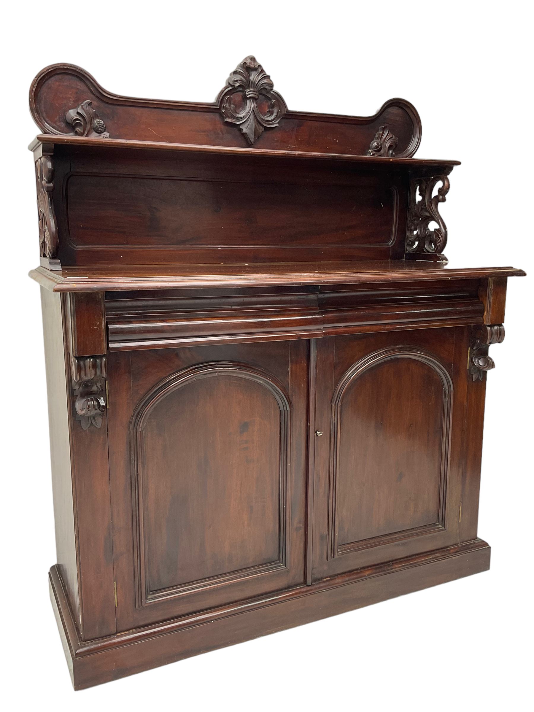 Victorian mahogany chiffonier, raised shaped back with foliage scroll carved mounts, on fretwork and carved bracket supports, moulded rectangular top over two frieze drawers and double panelled cupboard, on moulded plinth base