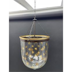 India Jane Interiors - pair of glass hanging lanterns, clear glass bell jars decorated with gold starburst patterns, each topped with a wide glass dish and suspended by three brass chains, the rim of each bell jar accentuated with a brass band, black metal hooks with a dragon head motif attach the chains to the rim