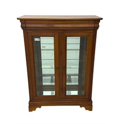 20th century cherry wood display cabinet, projecting cornice over two glazed doors with bevelled panes flanked by fluted support columns, enclosing three adjustable glass shelves with mirror-back surface, supported by shaped bracket feet