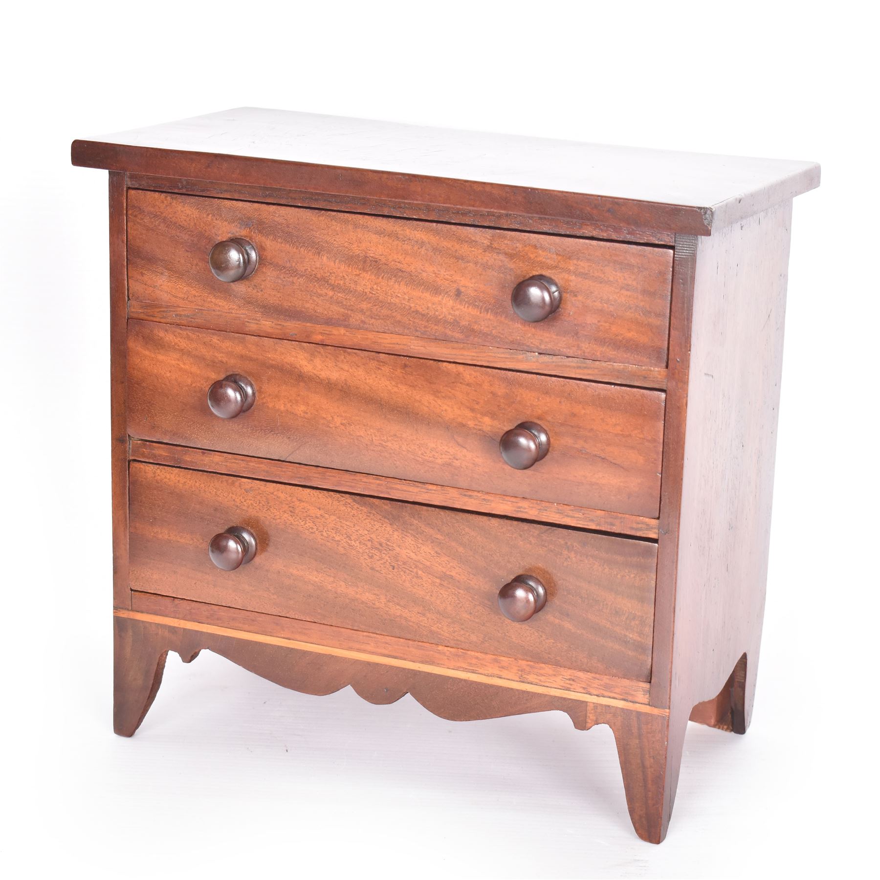 19th century mahogany miniature chest of drawers, with three graduating drawers, each with wooden handles, with inlaid shaped front and upon four bracket feet, H24cm