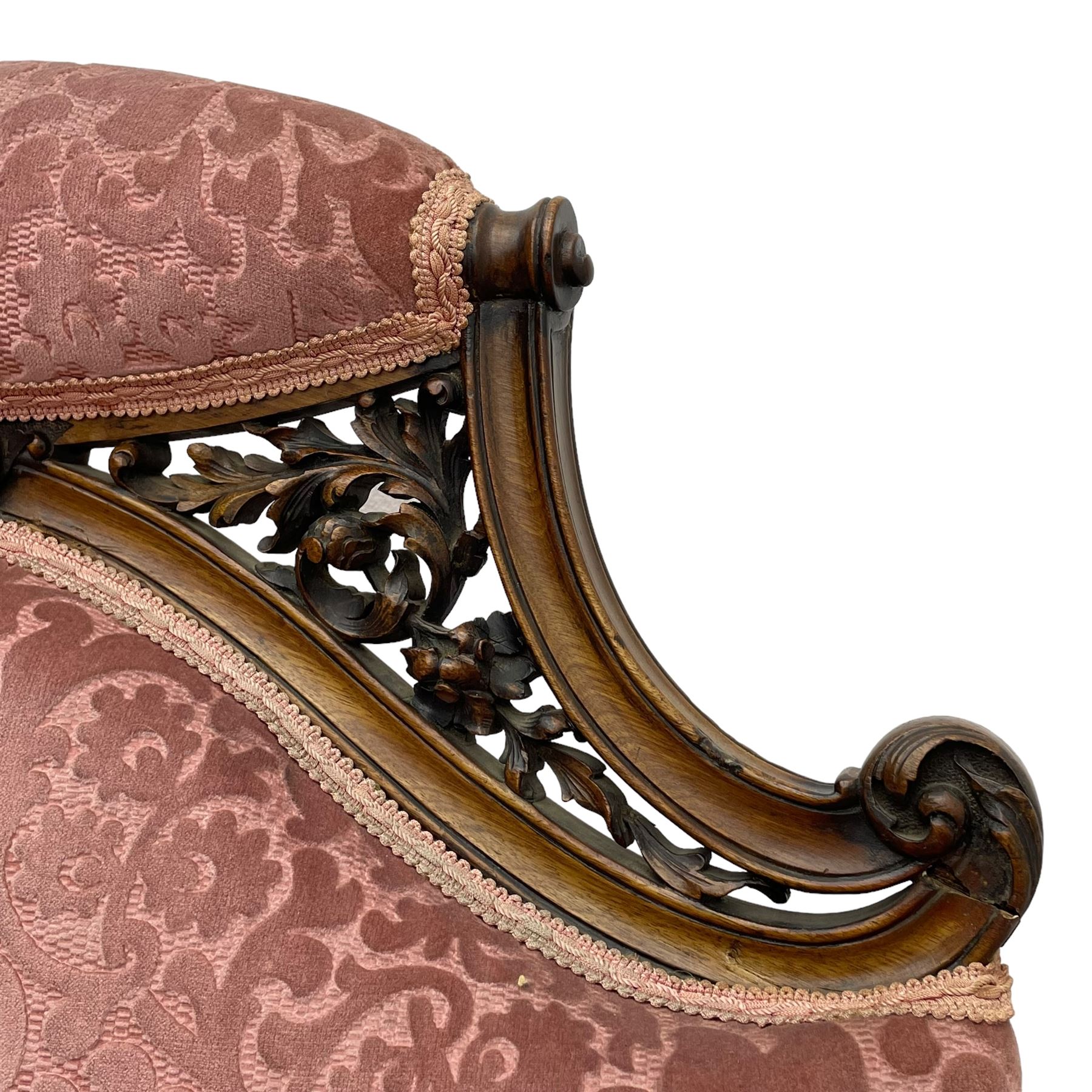 Late 19th century carved walnut framed armchair, the upper spandrels pierced and carved with curled acanthus leaves, upholstered in pink foliate pattern fabric, acanthus leaf carved and scrolled arm facias terminating to cabriole supports, leaf carved terminals 