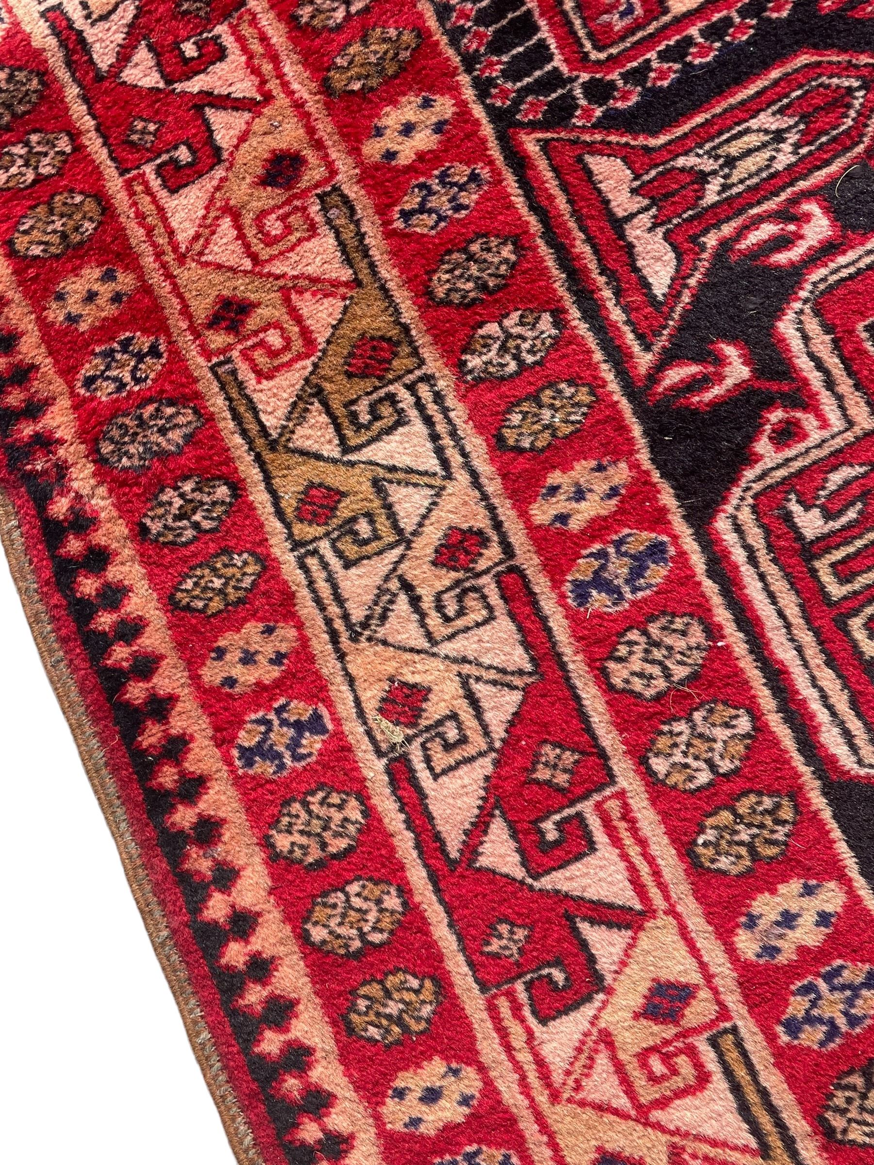 Persian Hamadan indigo and crimson ground rug, the field filled with three shaped medallions, overall geometric design, decorated with sandikli and hac motifs, geometric main border with repeating hooked motifs, within guard stripes decorated with small flower heads, outer crenelated fence band 