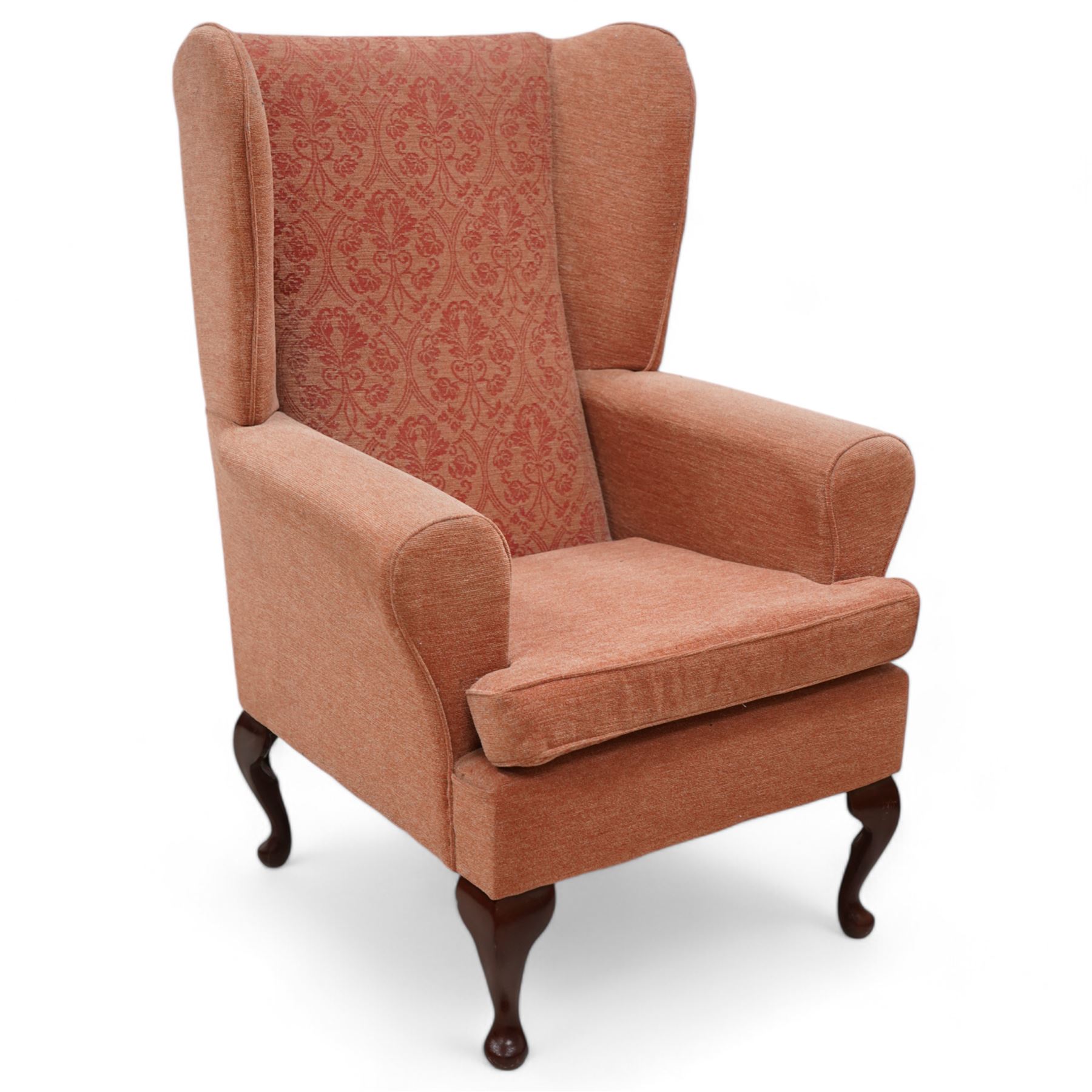 Hardwood-framed wingback armchair, upholstered in peach fabric, on cabriole feet 