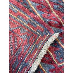 Meshwani indigo and maroon ground rug, the field decorated with a central lozenge with concentric borders containing hook motifs, enclosed by geometric zig-zag guard lines