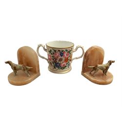 Pair of Art Deco dog bookends and a twin handled loving cup, painted with floral decoratio...