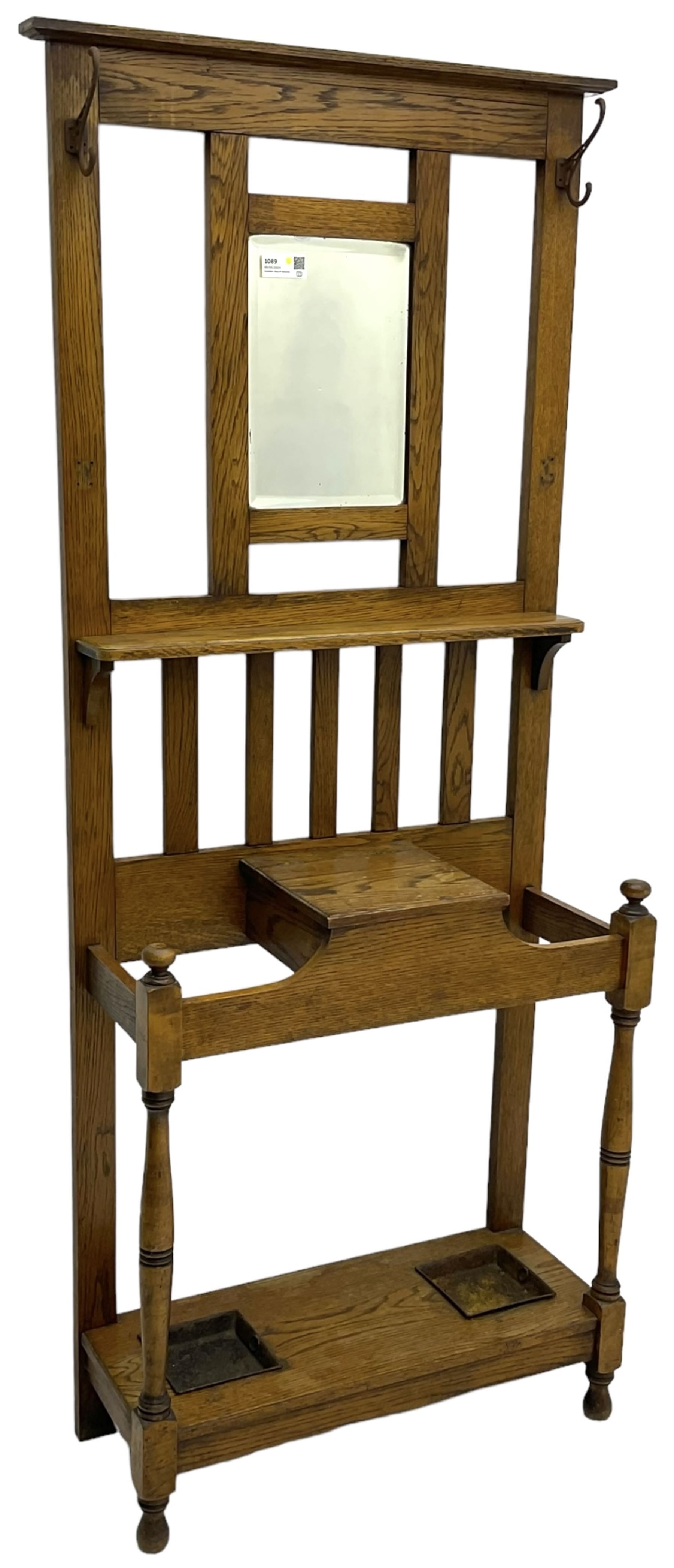 Early 20th century oak hall stand, bevelled mirror back over hinged compartment, on turned front supports 