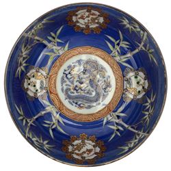 Set of four Japanese graduating porcelain bowls, each centrally painted with a coiled dragon in reserves, bamboo and foliate roundels against a blue ground, largest measuring D24.5cm (4)