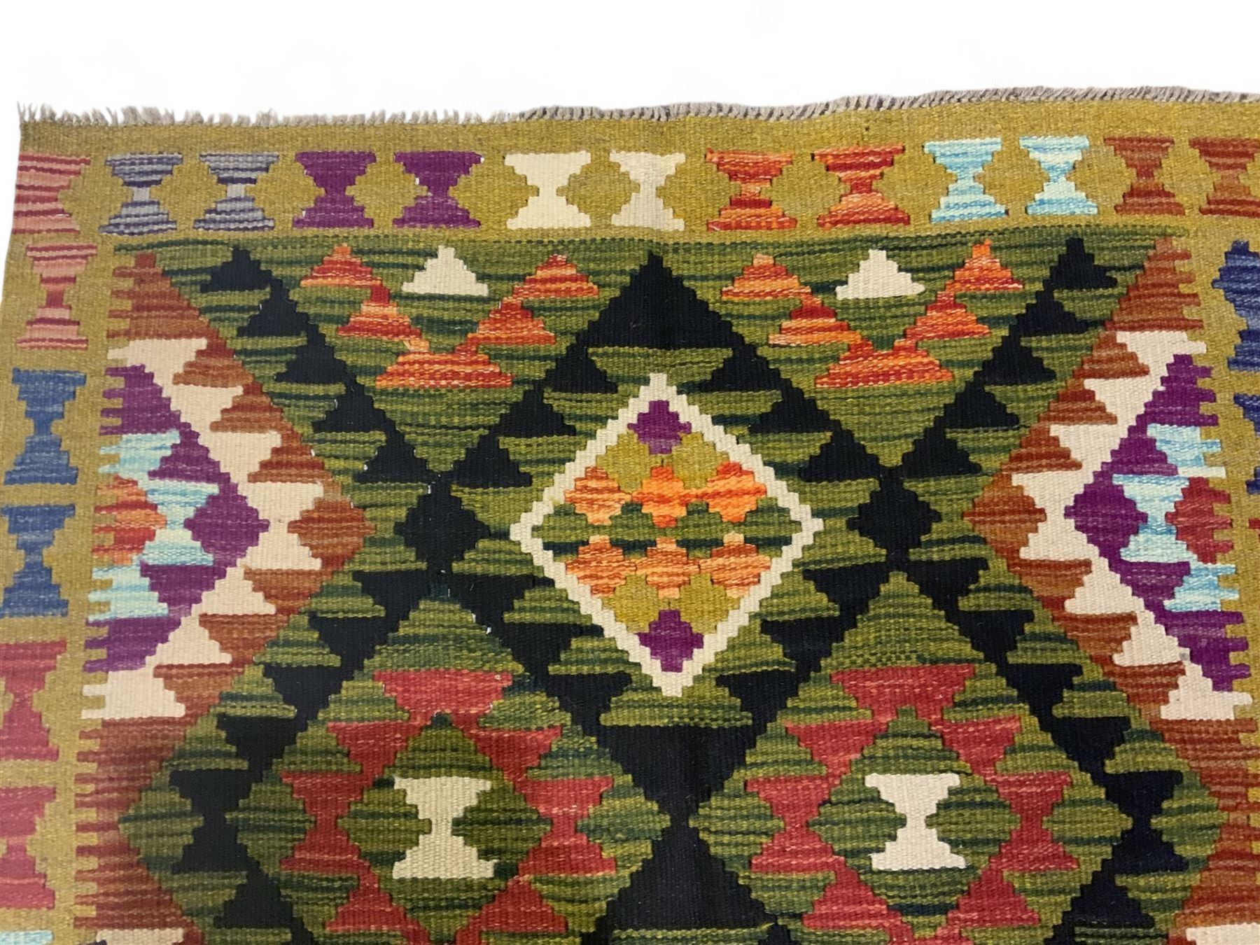 Chobi kilim multi-coloured rug, the field decorated with various lozenges with dark indigo borders, enclosed by a guard band with repeating broken-lozenge design