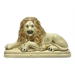 19th century salt-glazed stoneware door porter, as a recumbent lion, upon a stepped plinth base, H32