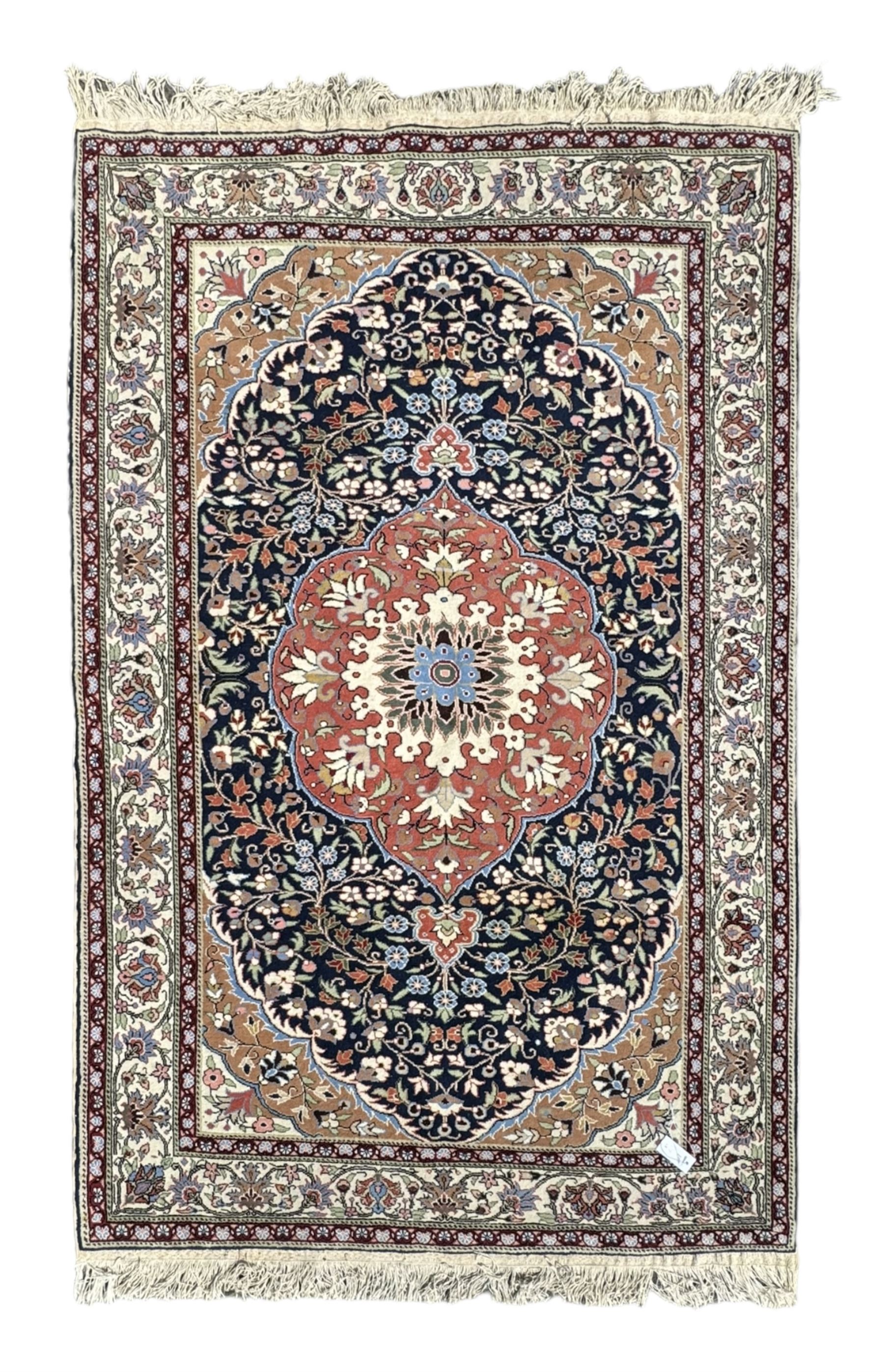 Indo-Persian indigo ground rug, the floral design peach medallion surrounded by trailing and interlaced branches and flower heads, the main border decorated with repeating stylised plant motifs within floral guard stripes 