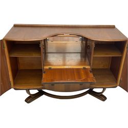 Beautility - mid-20th century walnut sideboard, fall-front with sliding top enclosing mirror interior, fitted with two drawers and flanking cupboards, on sledge feet with curved stretchers 