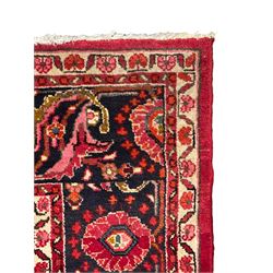 Persian Nanaj crimson ground carpet, the busy field filled with interconnecting stylised plant motifs with scrolling branches, the guarded indigo border decorated with repeating palmettes and foliate patterns