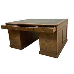 Late 19th century twin pedestal oak partner's desk, rectangular top with inset green leather writing surface, fitted with nine graduating drawers to each side, the rear drawers enclosed by panelled cupboards