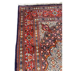 Persian Bidjar ivory and indigo ground rug, large central rosette medallion surrounded by floral herati motifs, crimson ground border decorated with repeating palmettes, within guard stripes decorated with small flower head motifs 