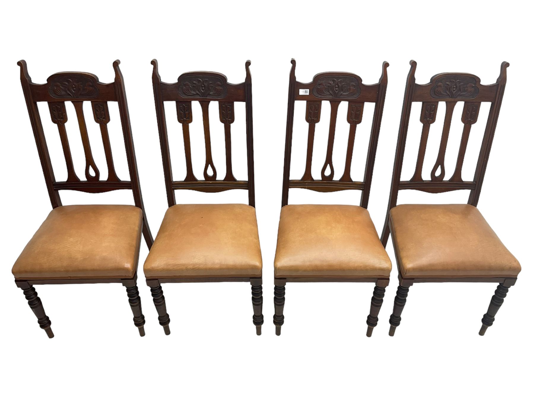 Set of four Edwardian walnut dining chairs, foliate carved high back over sprung seat upholstered in tan faux leather, raised on turned supports