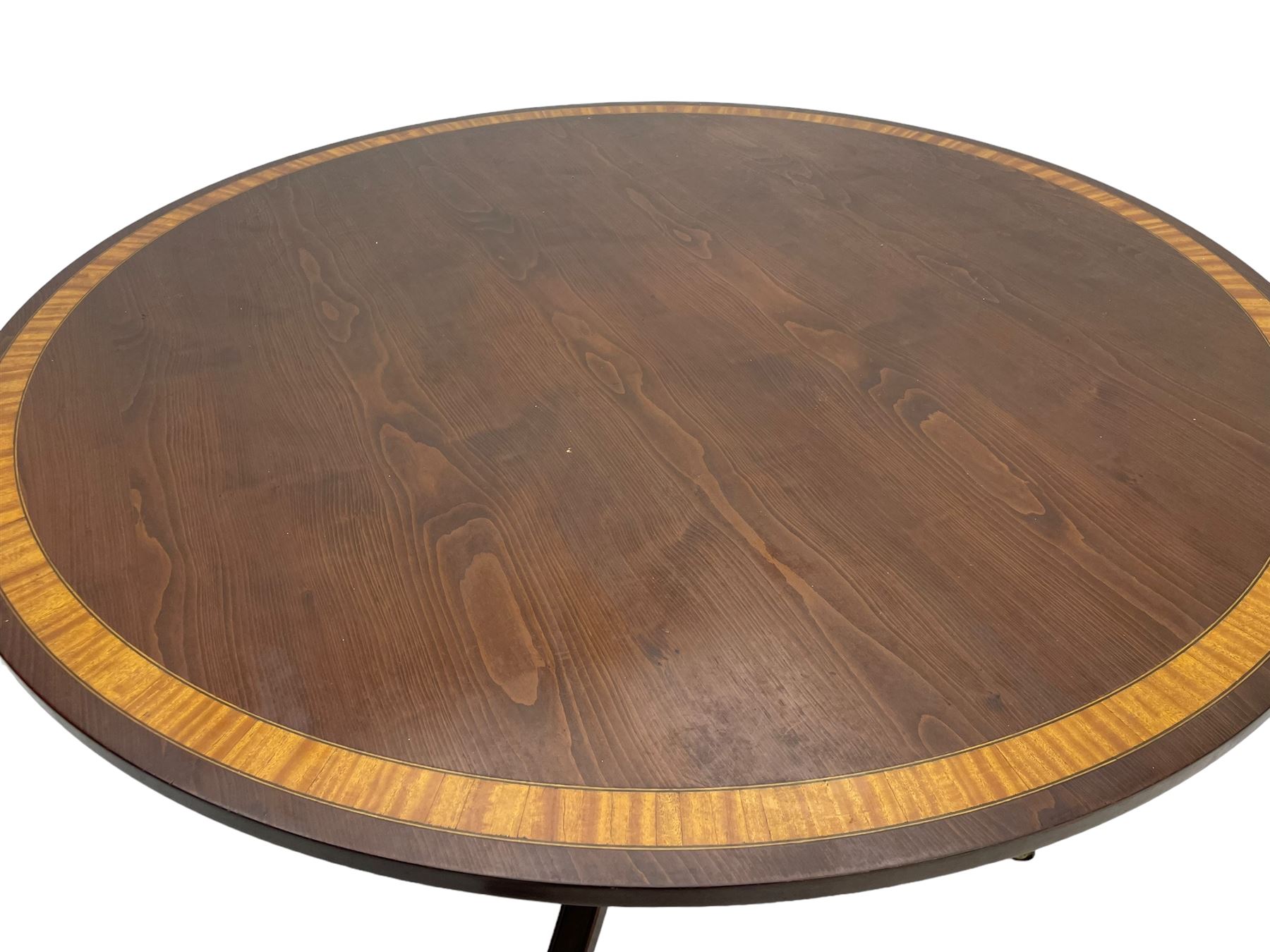 Georgian design inlaid chestnut wood centre table, the circular tilt-top inlaid with satinwood banding, gun barrel turned pedestal on four out-splayed supports, cast brass hairy paw castors, stamped 'P.H.R & Co. Holt, England' 