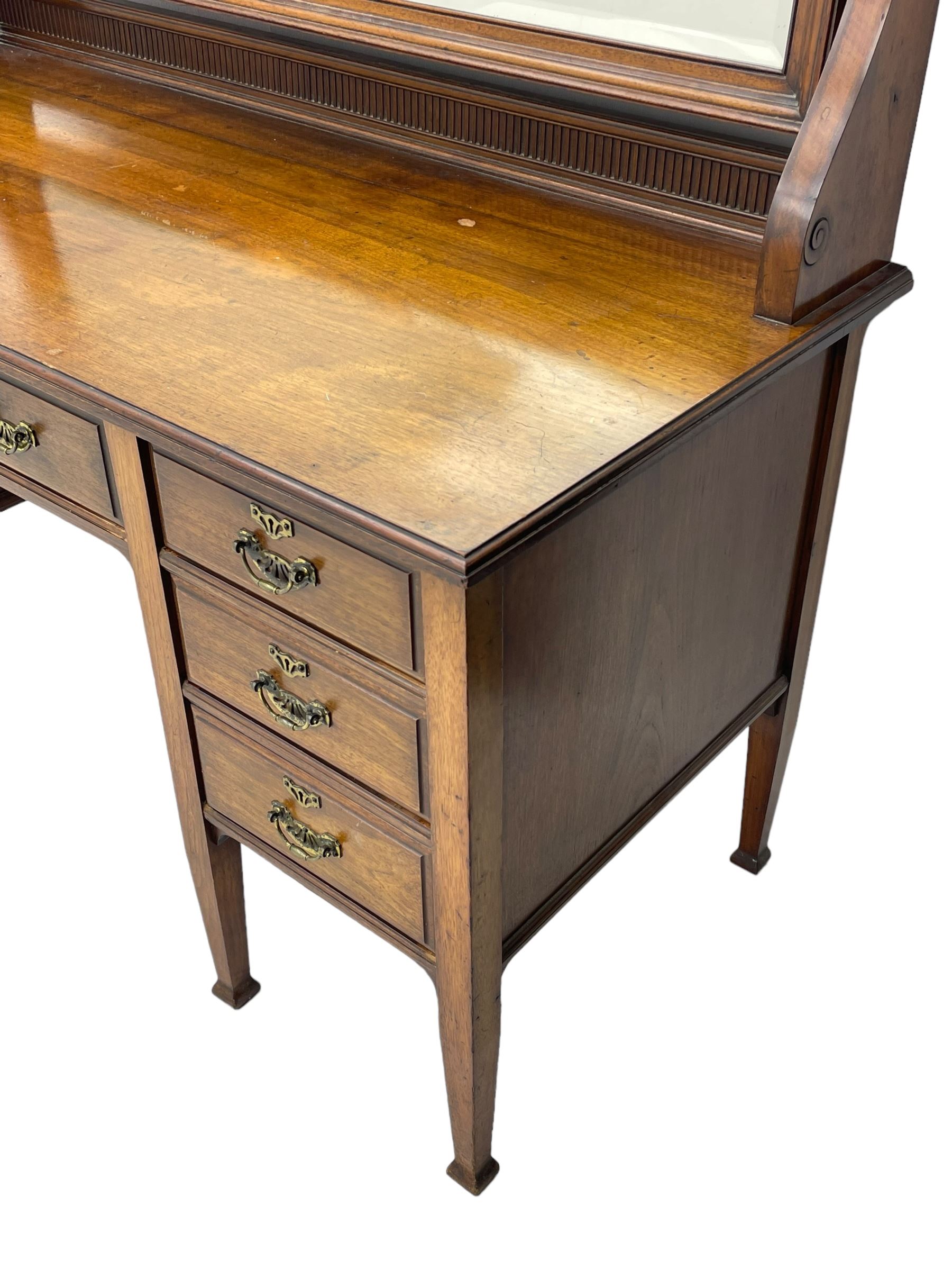 Late 19th century walnut dressing table, wide rectangular bevelled swing mirror in moulded frame, shaped horns carved with scrolls, moulded rectangular top over seven drawers, on square tapering supports with spade feet 