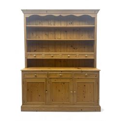 Traditional design waxed pine dresser, upper section with moulded cornice over scalloped frieze, fitted with two open shelves and four drawers, lower section with three drawers over three panelled cupboards, on plinth base