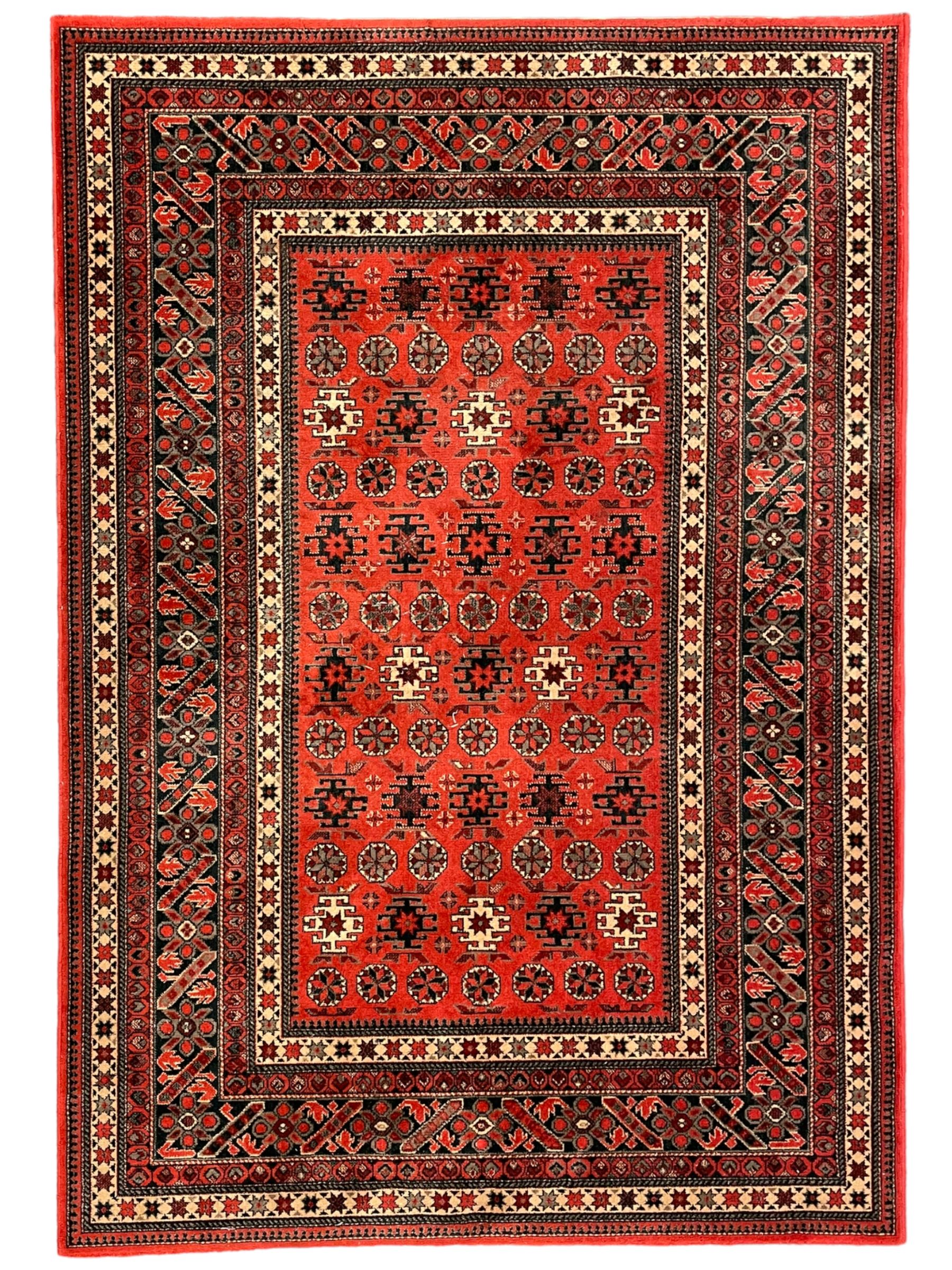 Persian design red ground rug, the field decorated with geometric motifs, repeating multiple band border 