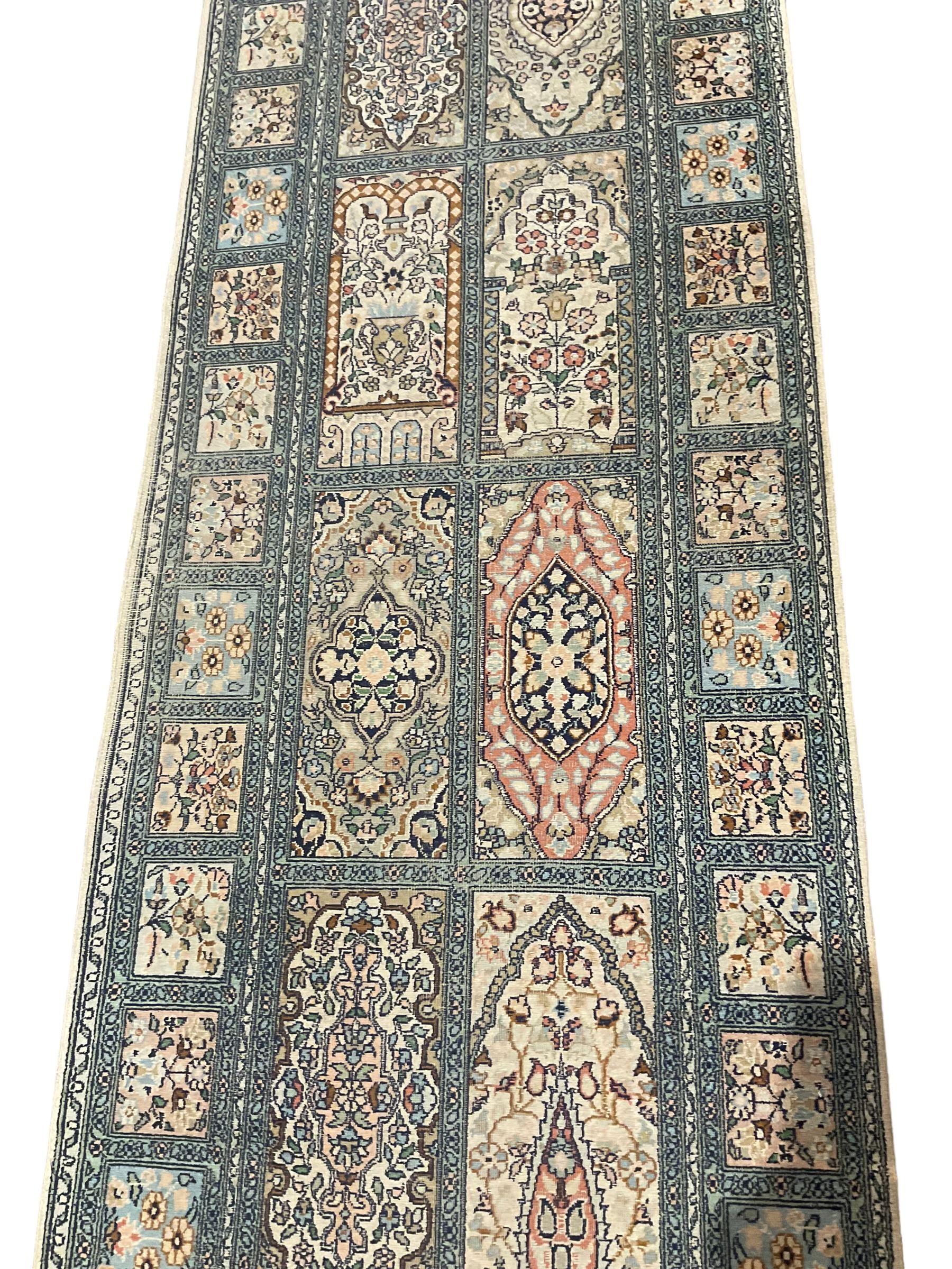 Fine Persian Kashmir ivory and pale indigo ground runner rug, the field decorated with sixteen rectangular panels depicting Mirab motifs and other traditional carpet designs, the border with repeating square panels of floral bouquets and foliate patterns