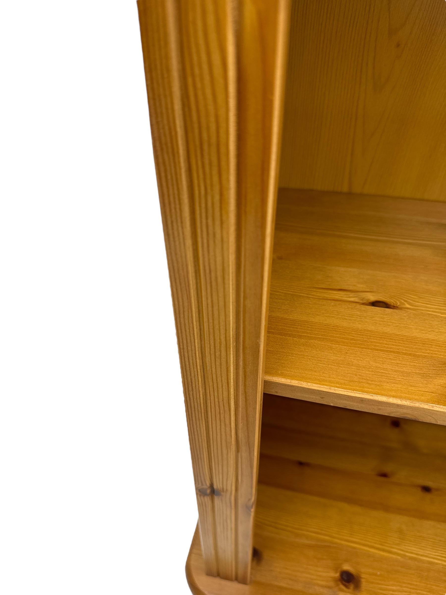 Traditional pine open bookcase, featuring arched top section flanked by fluted side supports, two adjustable shelves and cast iron coat hook with cat motif to the left side, standing on round bun feet 