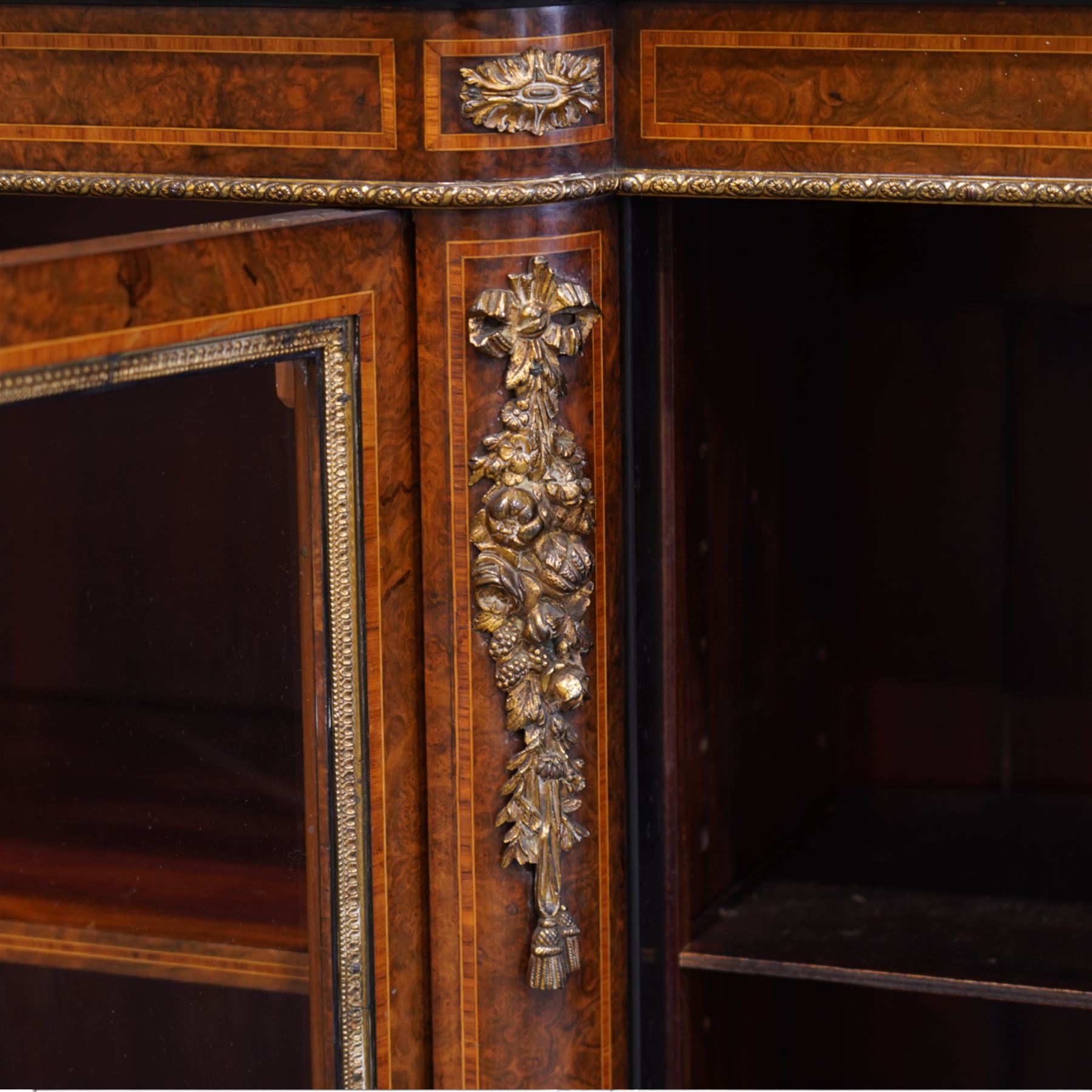 Victorian figured walnut and gilt metal mounted breakfront bookcase, satinwood banded top with gilt metal edging, the frieze inlaid with satinwood bands and mounted foliate castings, six shelves enclosed by four glazed doors each with cast foliate slips, the uprights decorated with ribbon tie and flower heads gilt metal mounts, on plinth base with egg and dart upper edge 