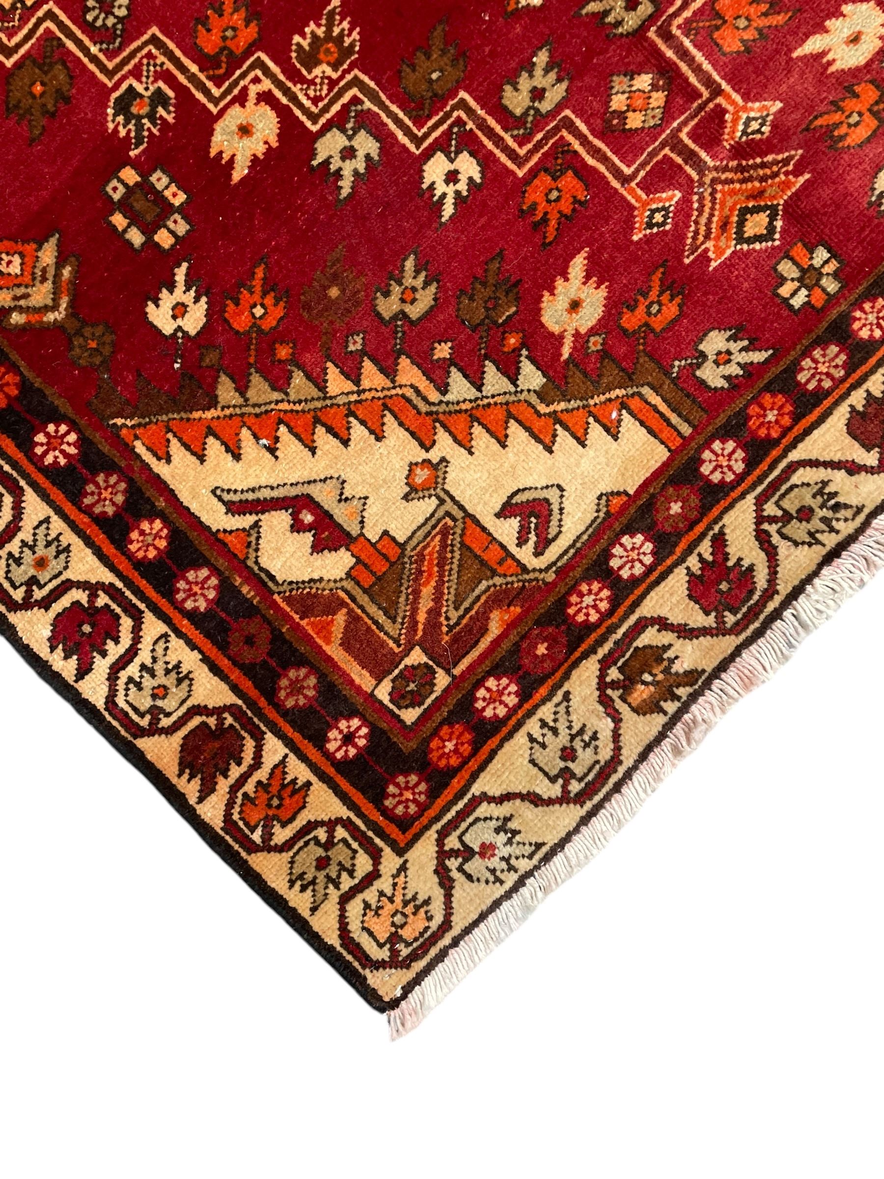 Persian crimson ground rug, the field decorated with three medallions within stepped borders, decorated all over with small stylised plant motifs, trailing flower head outer band and floral pattern border 