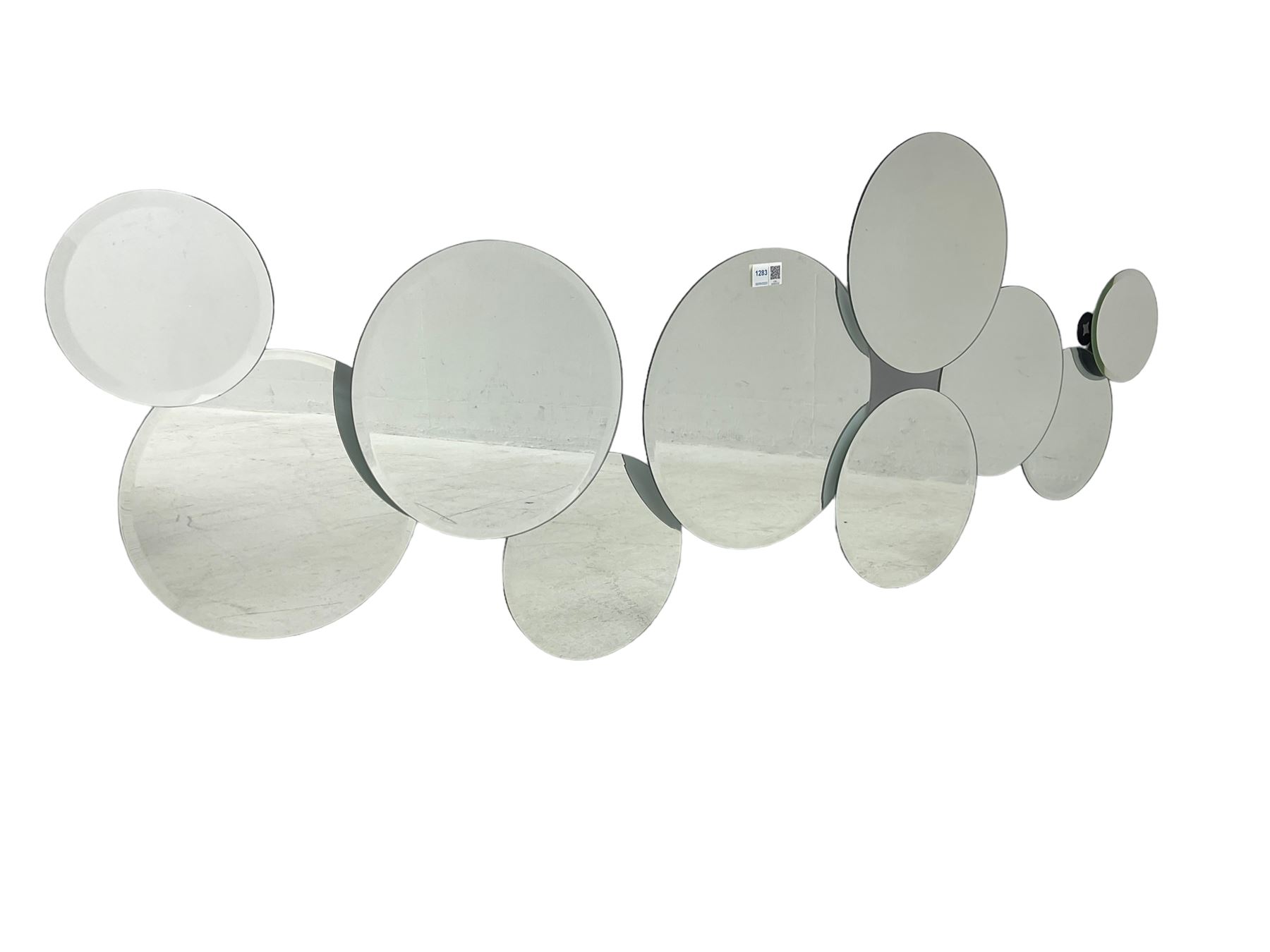 Contemporary abstract circular mirror, comprised of interconnecting bevelled plates of varying sizes