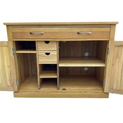 Contemporary light oak sideboard desk, rectangular top with full length drawer, hinged front panel revealing pull-out keyboard tray, over two panelled doors enclosing an assortment of shelves and compartments with cable management holes, on plinth base