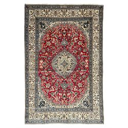 Persian Kashan crimson rug, central cusped medallion surrounded by interlacing branches decorated with leaves and palmettes, ivory ground spandrels and border decorated with scrolling branches and stylised plant motifs, within guard stripes  