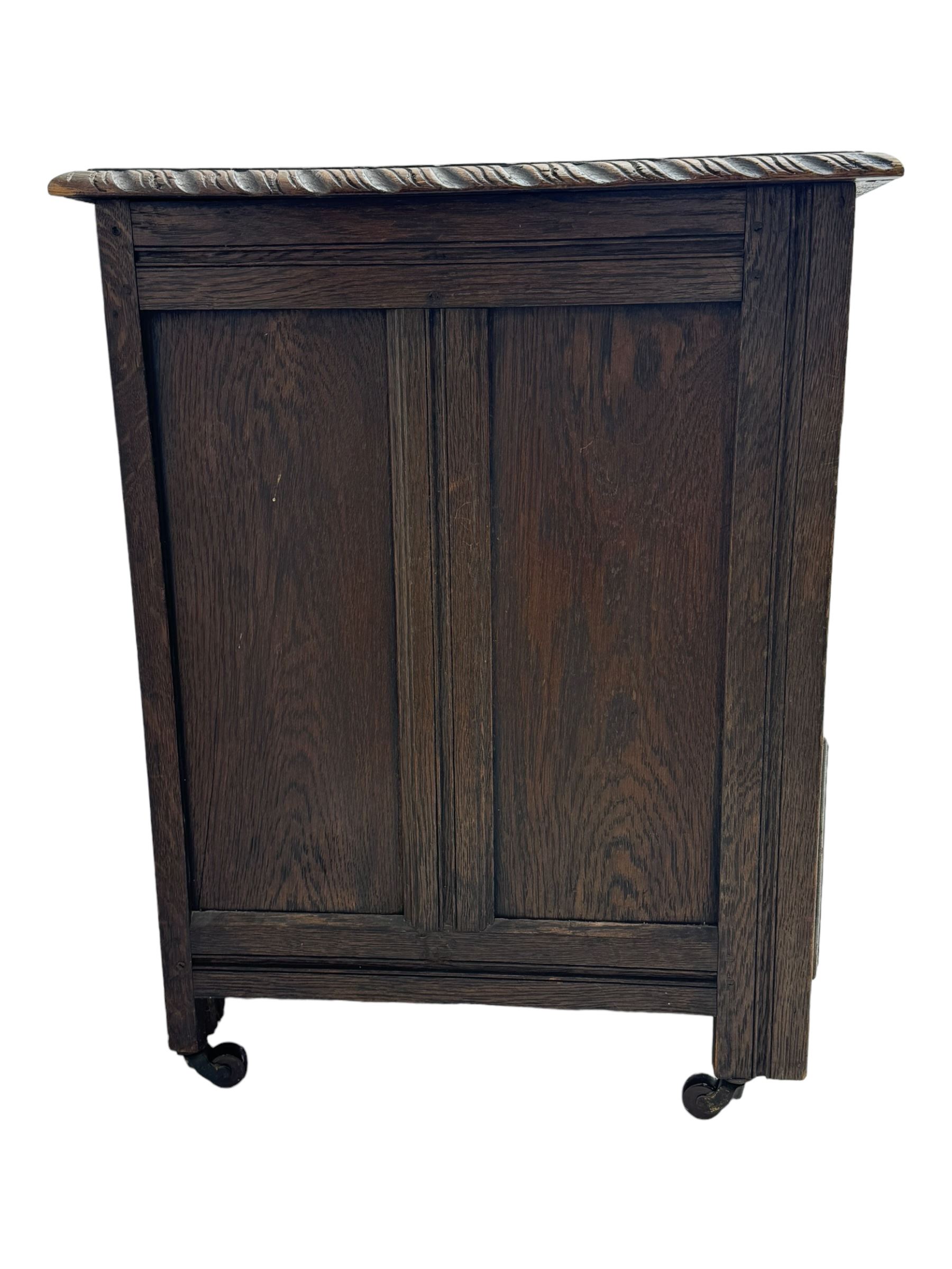 Victorian carved oak kneehole desk, the rectangular top with carved edge, above central drawer with carved front and brass handles, central kneehole with cupboard door, flanked by two banks of three graduating drawers each with similarly carved decoration, on shaped plinth base with castors