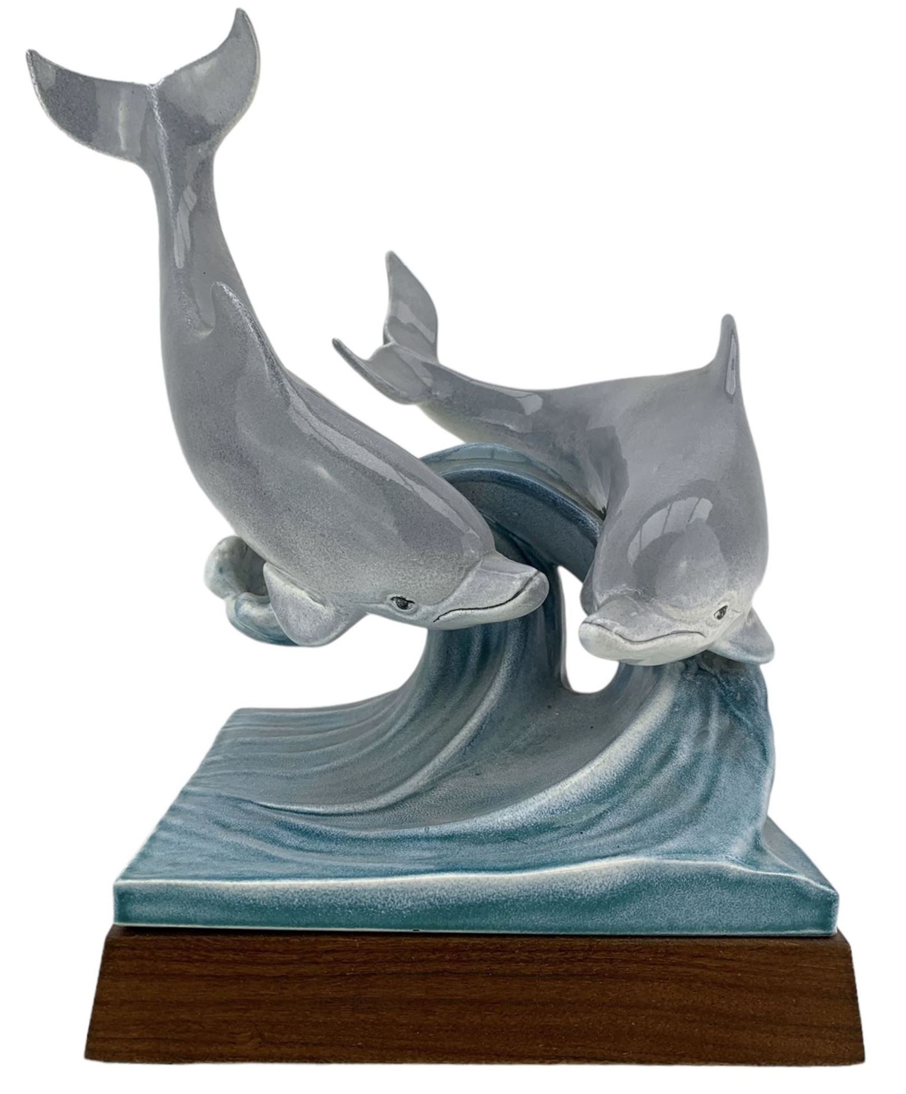 Tony Morris for Poole Pottery, leaping dolphin group, modelled over waves and mounted on a wooden base, H29cm. This model is a duplicate of a sculpture presented to Queen Elizabeth II and the Duke of Edinburgh on their visit to Poole Pottery in 1979, the original cast was destroyed after the production of the duplicate. Provenance: Arnold Smith, Chairman of Pool Potteries Collection