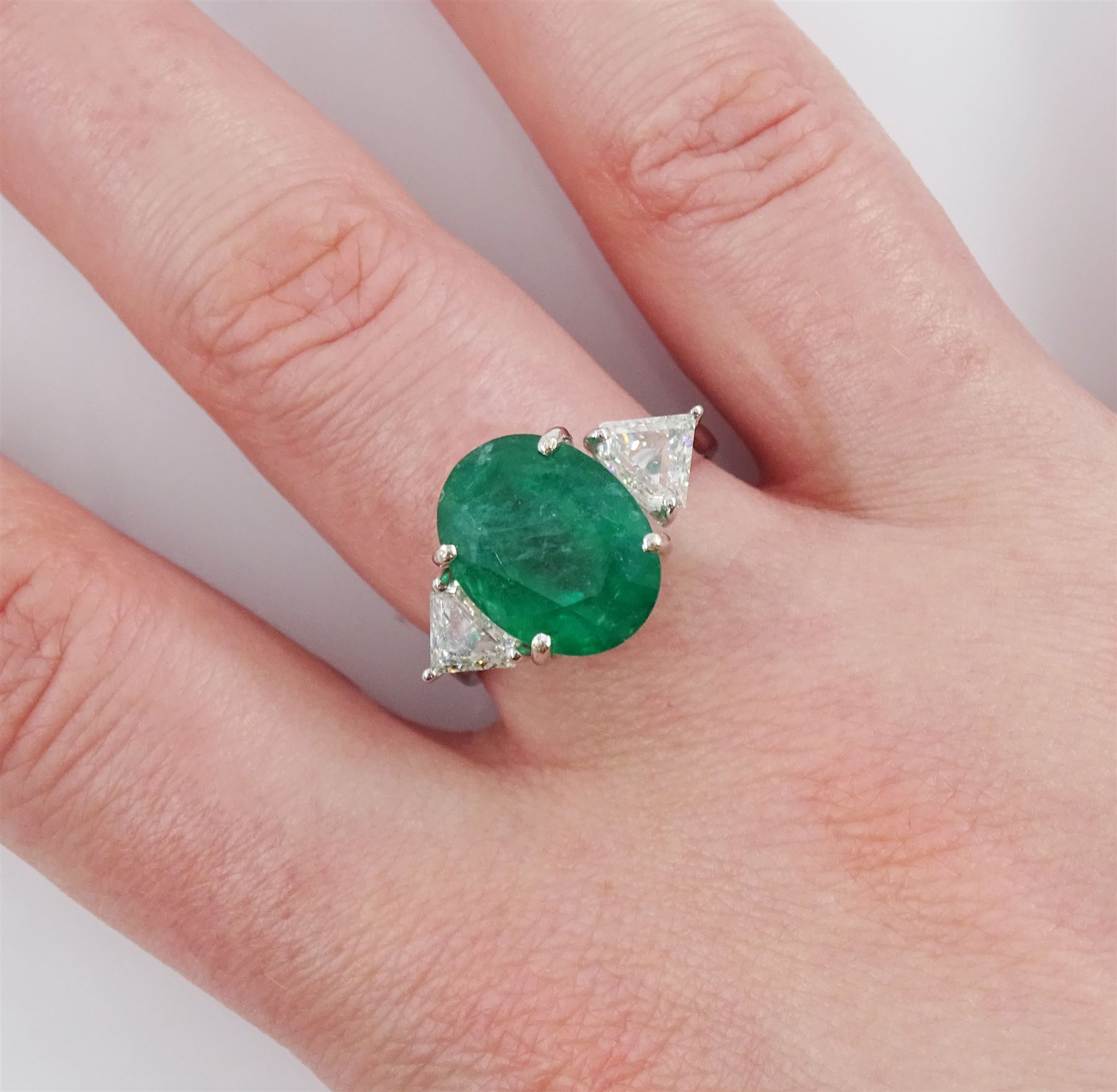 18ct white gold three stone oval cut emerald and trillion cut diamond ring, stamped, emerald approx 5.65 carat, total diamond weight approx 0.65 carat