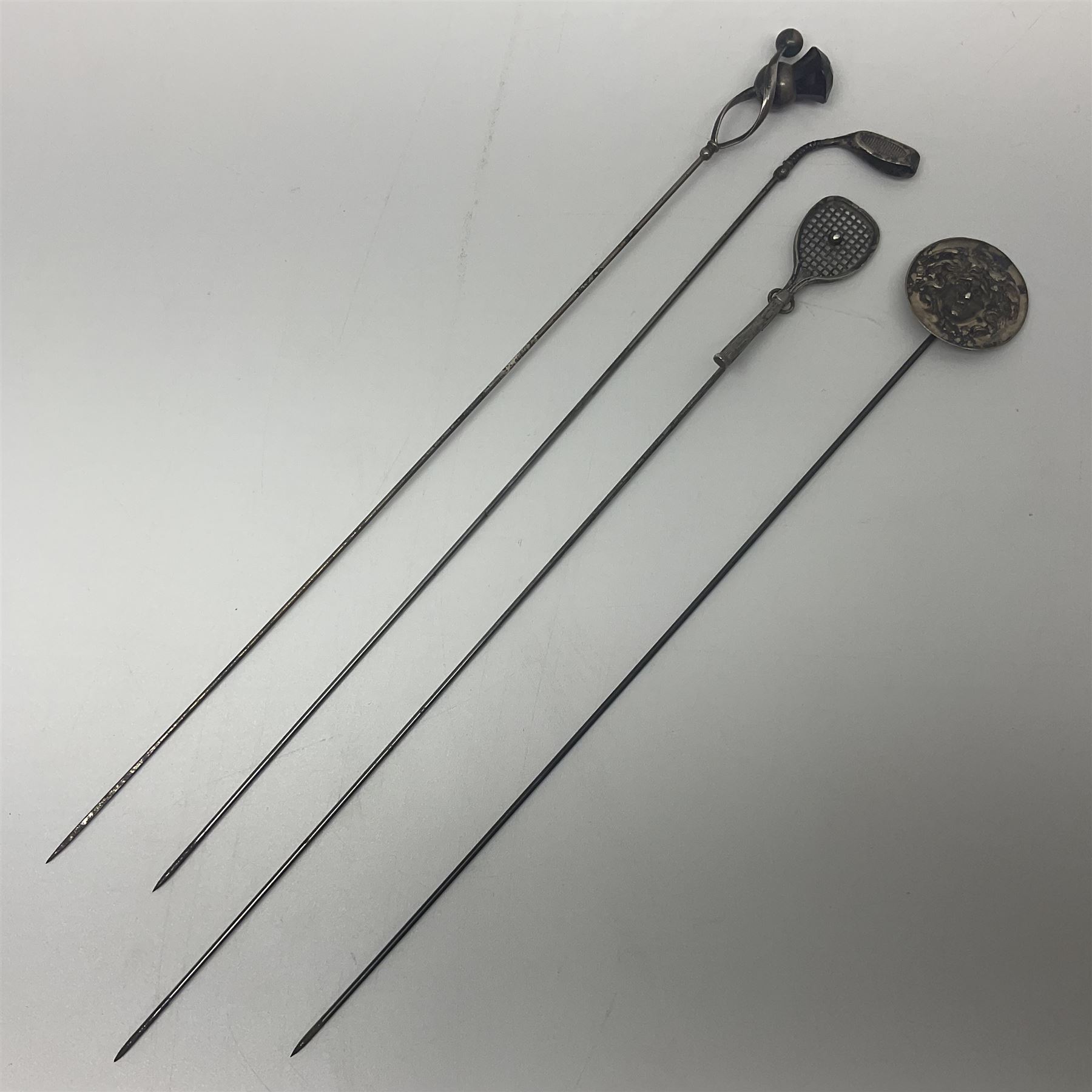 Silver hatpin modelled as a thistle, by Charles Horner, together with three other silver hatpins, modelled as a tennis racket, golf club and Medusa mask, all hallmarked 