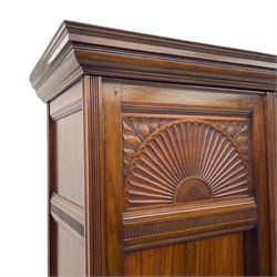 Late Victorian walnut triple wardrobe, projecting moulded cornice over central bevelled mirror door and flanking panelled doors, the top panels carved with fluted fans and stylised leaf motifs, the interior fitted with three linen slides, two drawers and hanging space, two long drawers to base, reed moulded uprights and vertical fluted horizontal rails 