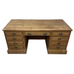 20th century waxed pine kneehole desk, rectangular top over nine drawers with cup handles, on moulded plinth base