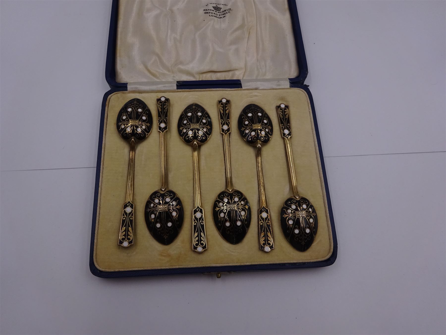 Set of six 1930s silver-gilt and enamel coffee spoons, the bowls and finials decorated verso in black and white enamel, hallmarked Turner & Simpson Ltd, Birmingham 1933, contained within fitted case