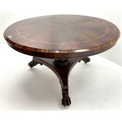 Regency mahogany circular breakfast table, the highly figured segmented veneer top with rosewood band, turned column on platform base with carved paw feet, circular glass top 