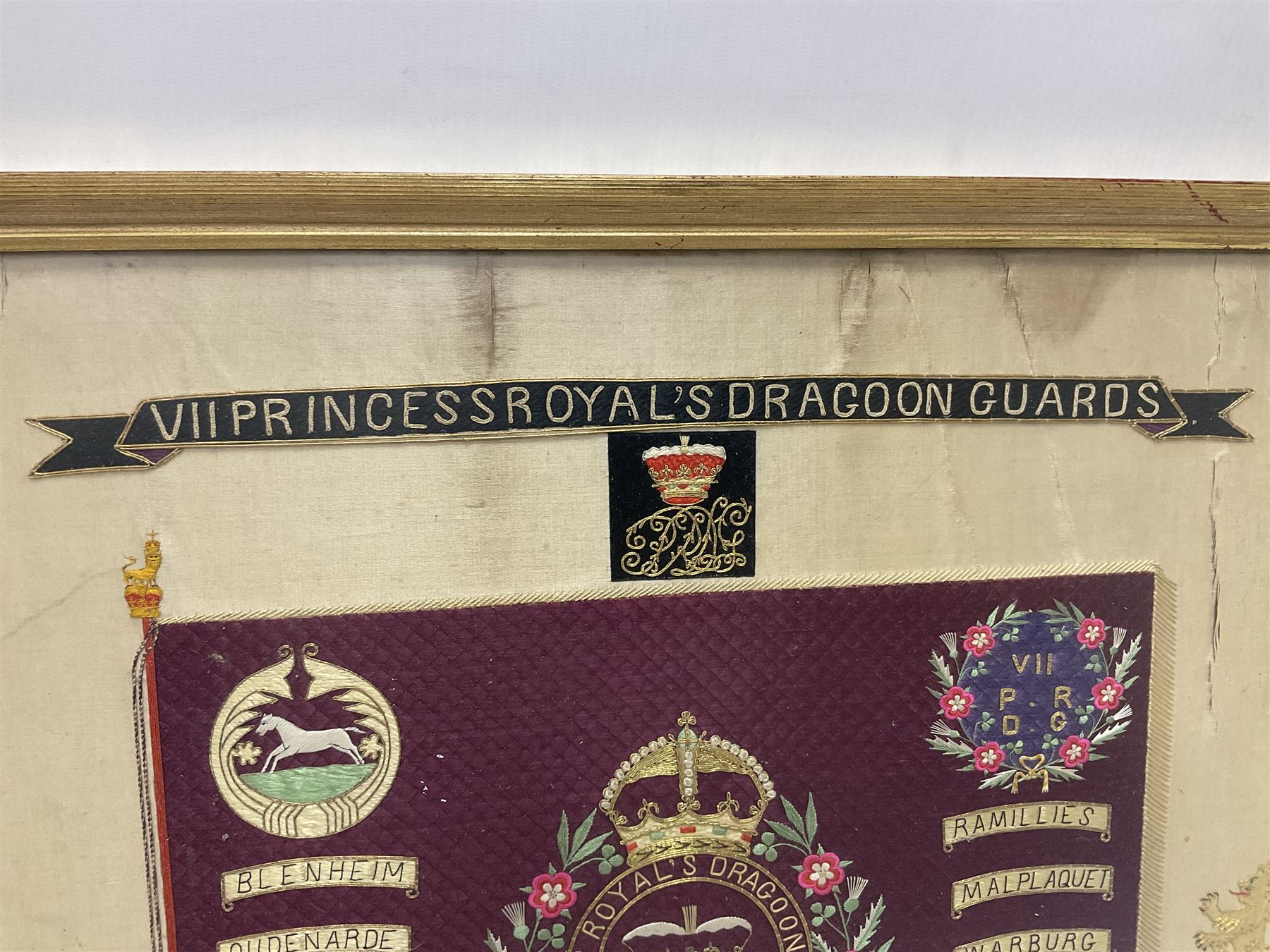 Commemorative Military needlework, headed 'VII Princess Royal's Dragoons Guard, the central flag has the regimental title, surrounded by a Union wreath of roses, thistles and shamrocks, topped with a crown, the Hanoverian white horse features in two corners, framed H58cm, L73cm