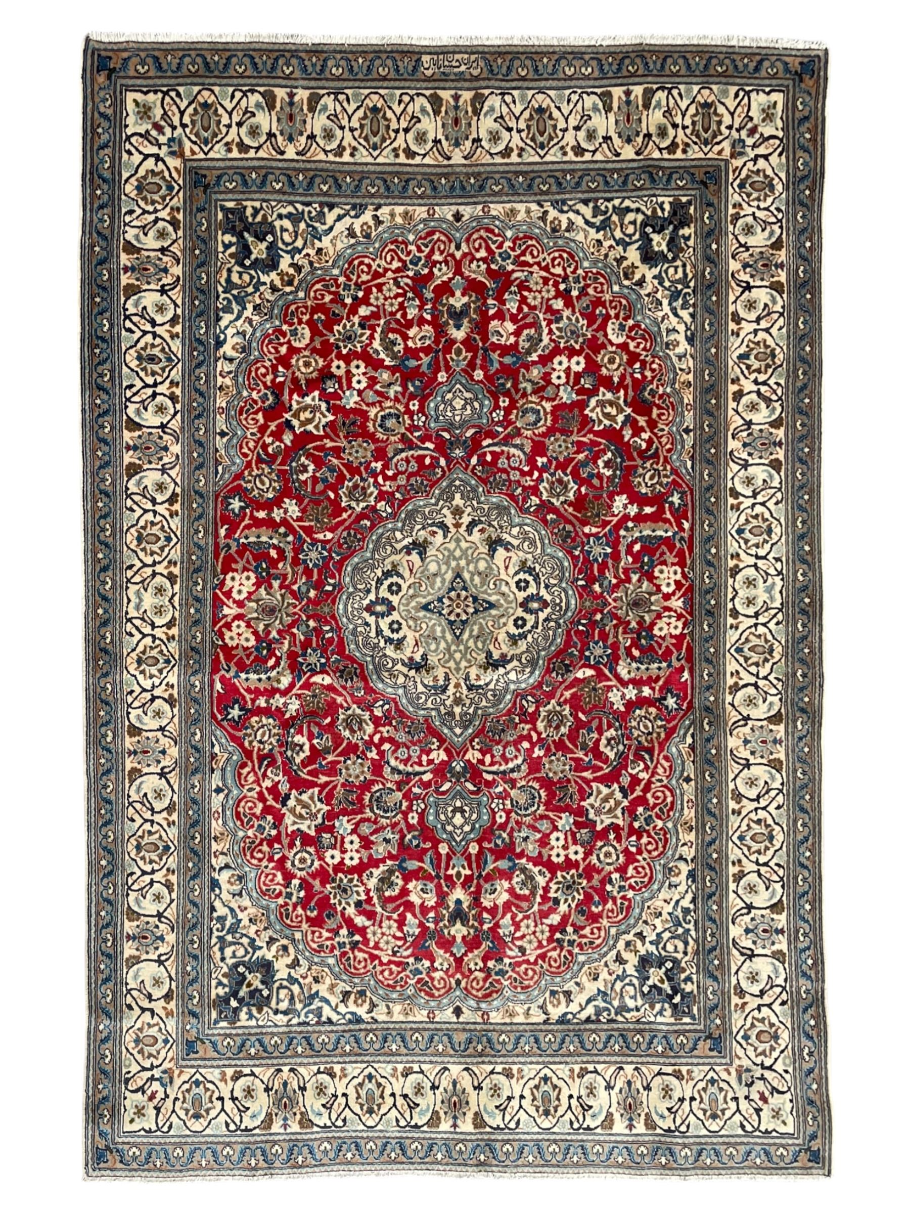 Persian Kashan crimson rug, central cusped medallion surrounded by interlacing branches decorated with leaves and palmettes, ivory ground spandrels and border decorated with scrolling branches and stylised plant motifs, within guard stripes  