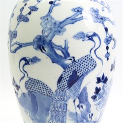 Pair of 19th/ early 20th century Chinese blue and white vases and covers, each of baluster form, painted in underglaze blue with peacocks stood on a rocky base amid blossoming peony and prunus flowers, the covers with dogs of fo finials, four character Kangxi marks beneath, H33cm 