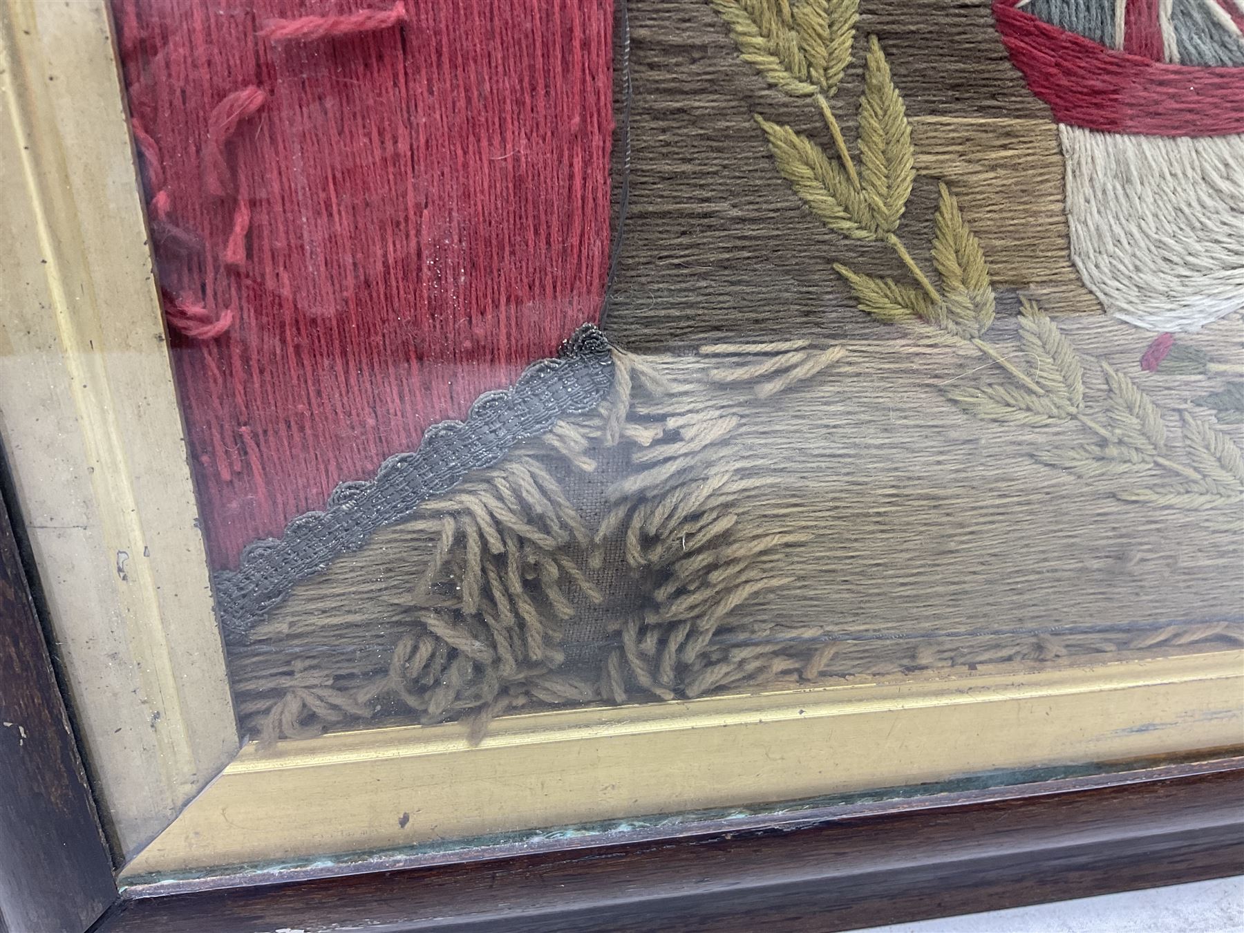 19th century woolwork, depicting a clipper ship, fully rigged over black hull with white ports, within a border of ensigns and flags and beaded crown above, in glazed wooden frame, H57cm