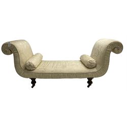 Victorian mahogany framed window seat day bed, the scrolled arms and seat upholstered in ivory foliate patterned damask fabric with matching ropetwist piping, raised on turned supports with castors