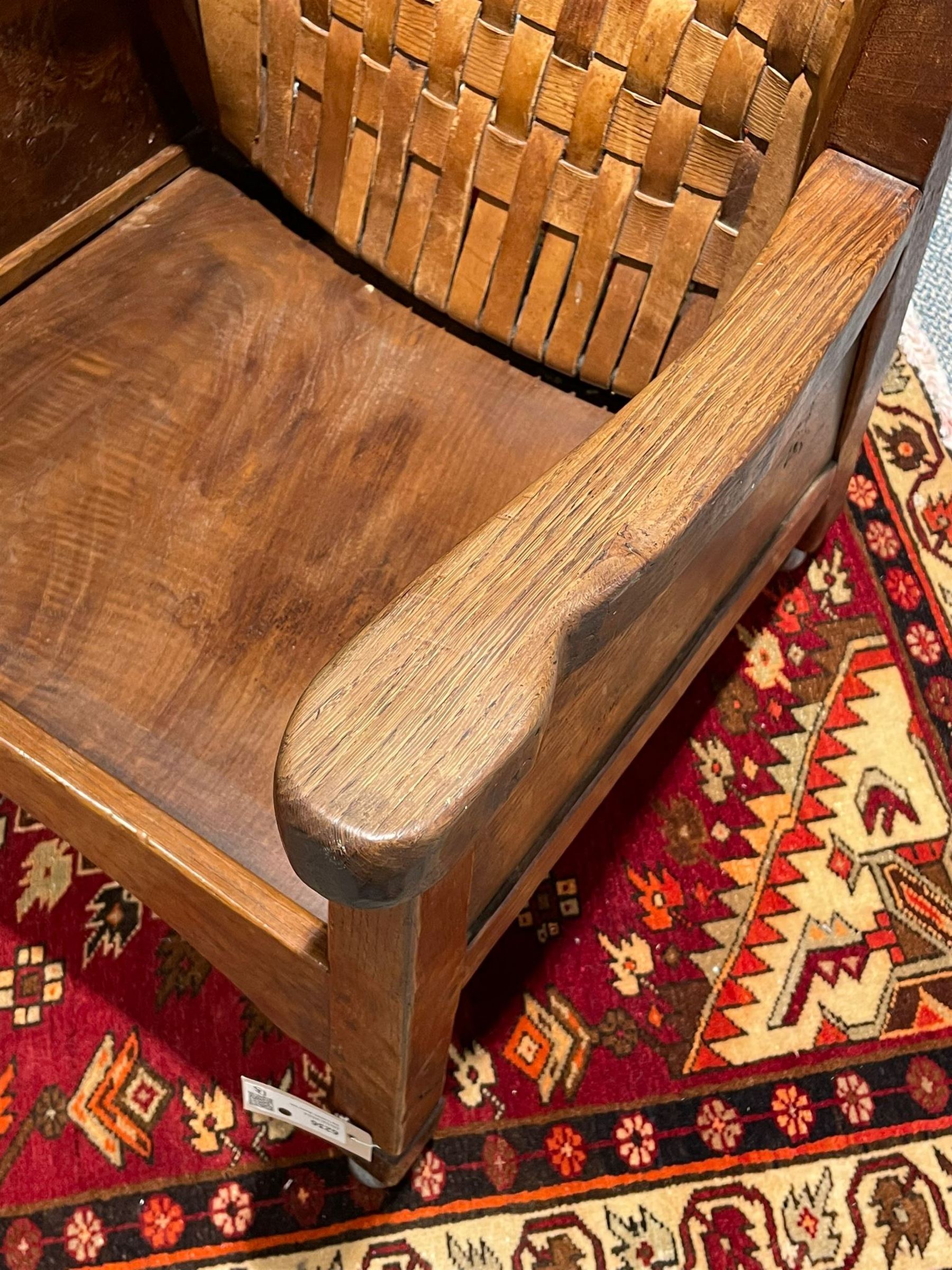 Mouseman - unusual circa. 1930s adzed oak tub-shaped armchair, barrel-back with woven leather, the upright carved with mouse signature, figured panelled sides enclosing panelled seat, arched seat rail, stile supports with block feet on castors, by the workshop of Robert Thompson, Kilburn  

Notes: made by apprentice Graham Hayes (1914-1943). Hayes went on to become a founding member of the Small Scale Raiding Force (SSRF), a special commando unit under the Special Operations Executive (SOE), established by Winston Churchill in 1940. Tragically, he was captured in 1942 and held prisoner by the Gestapo until his execution in 1943. Recently, Hayes has been featured in Guy Ritchie's film 'The Ministry of Ungentlemanly Warfare' under the name 