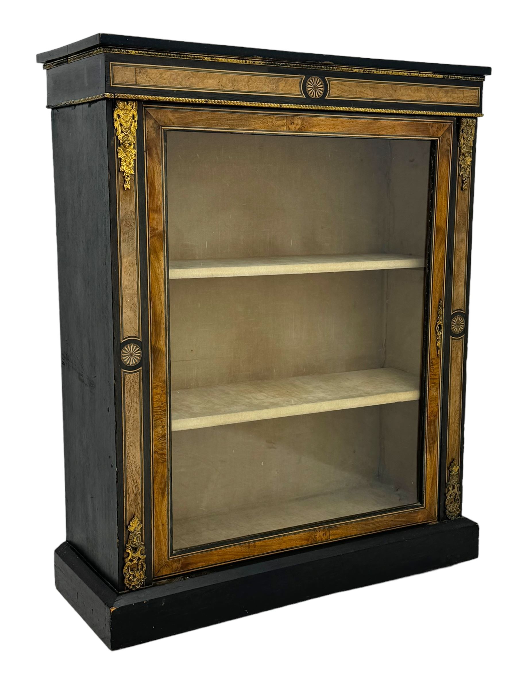 Victorian ebonised and walnut pier cabinet, rectangular top over figured frieze with central star motifs, enclosed by single glazed door, decorated with cast gilt metal mounts and beading, on chamfered plinth base 