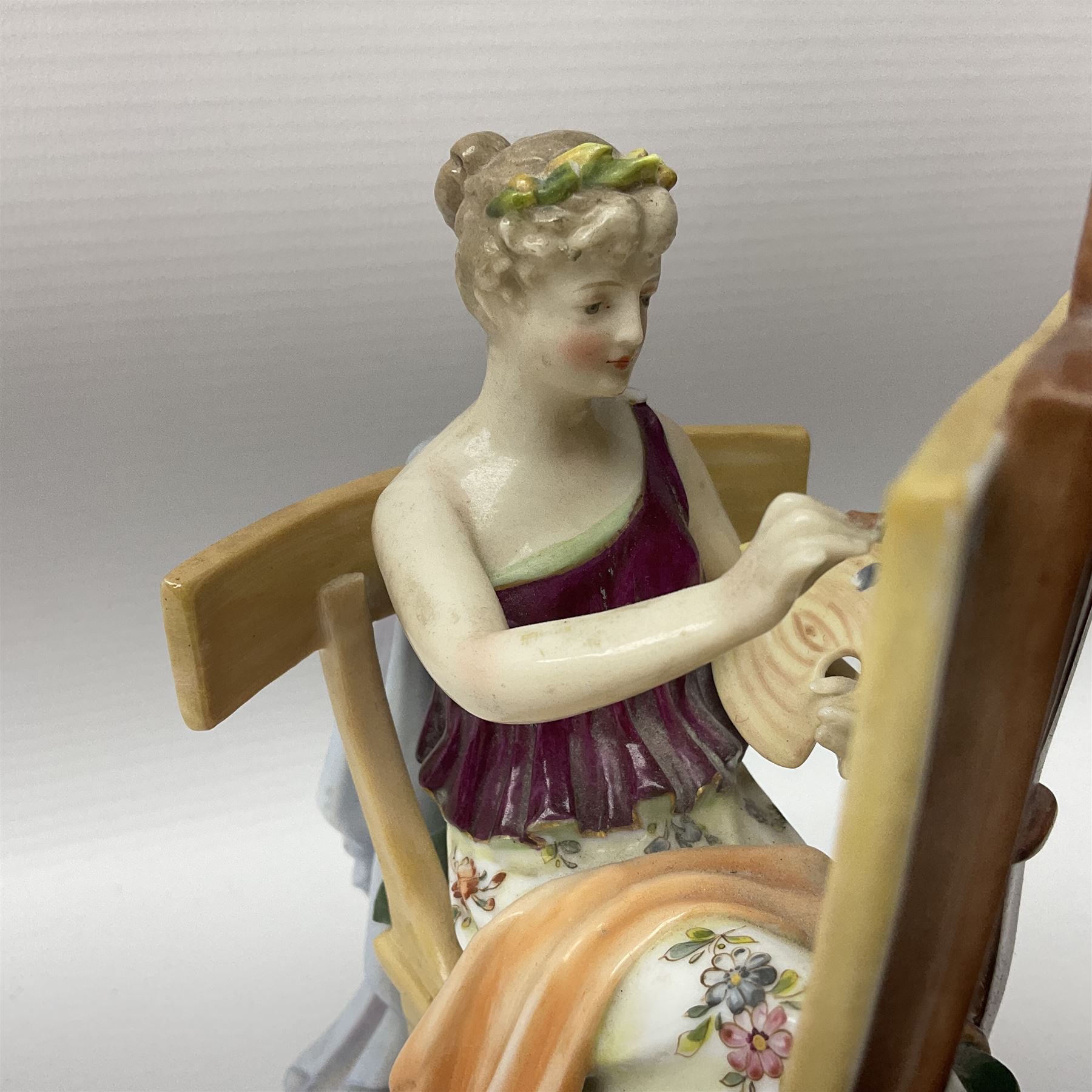 Pair of late 19th/early 20th century Naples figures modelled engaged in the arts, the first example modelled as a female figure seated before an easel, painting a figural scene, the second modelled as a female figure seated before a bust with scultping tools in hand, each upon an oval base with naturalistic painted ground, each with blue crowned N mark beneath, each approximately H16cm, including base L15xm
