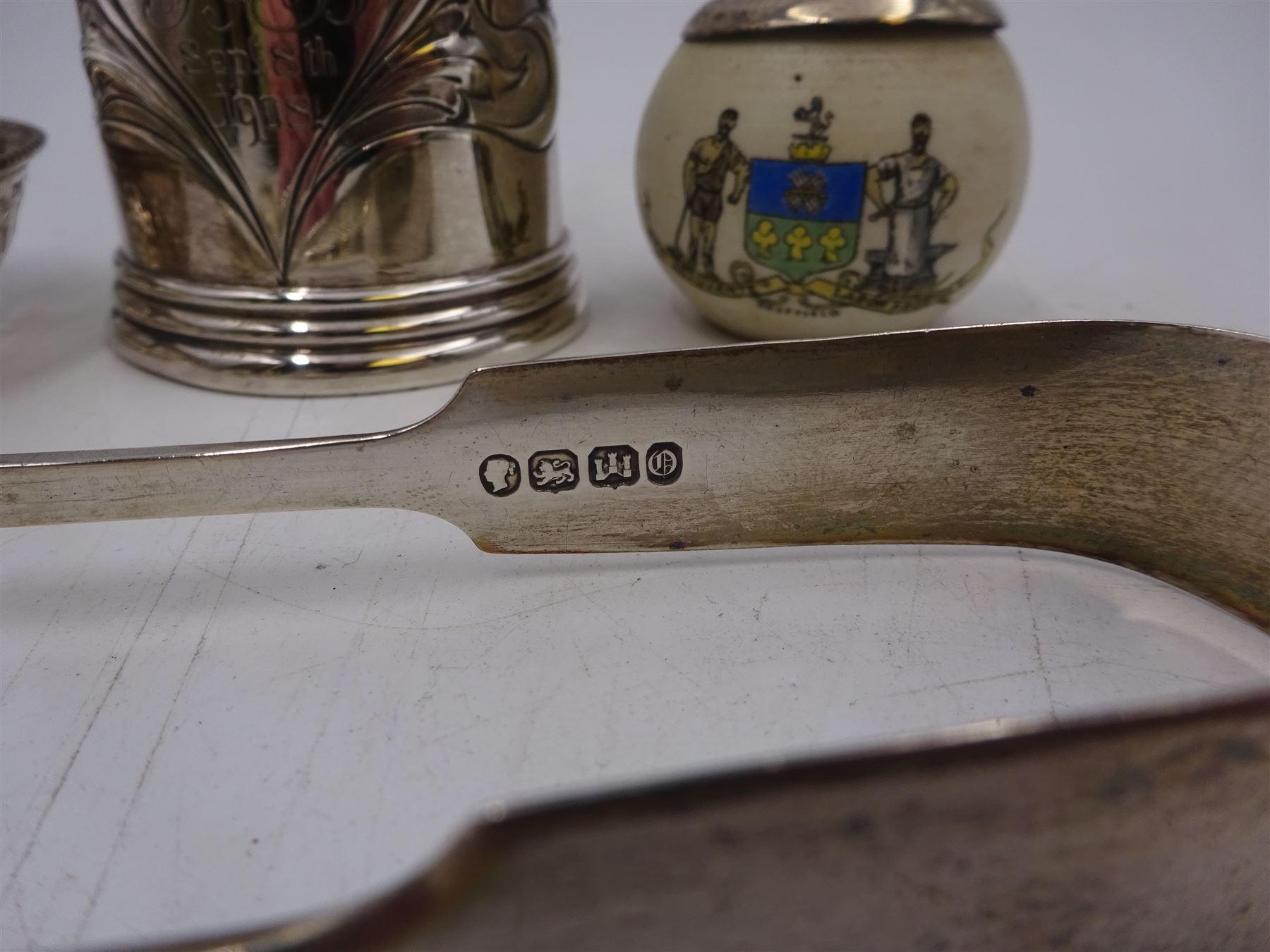 Group of silver, comprising Edwardian christening mug, of slightly tapering form, embossed with floral decoration and engraved initials and date, hallmarked Cooper Brothers & Sons Ltd, Sheffield 1906, a crested ware jar with silver collar, pierced pin dish and a pair of sugar tongs, all hallmarked 