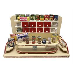 Late 1950s continental red and white painted wooden diorama of a grocery shop interior with fitted shelves and drawers and freestanding 'glazed' counter, fully stocked with miniature tin cans and packets of food L42cm H23cm D22cm
