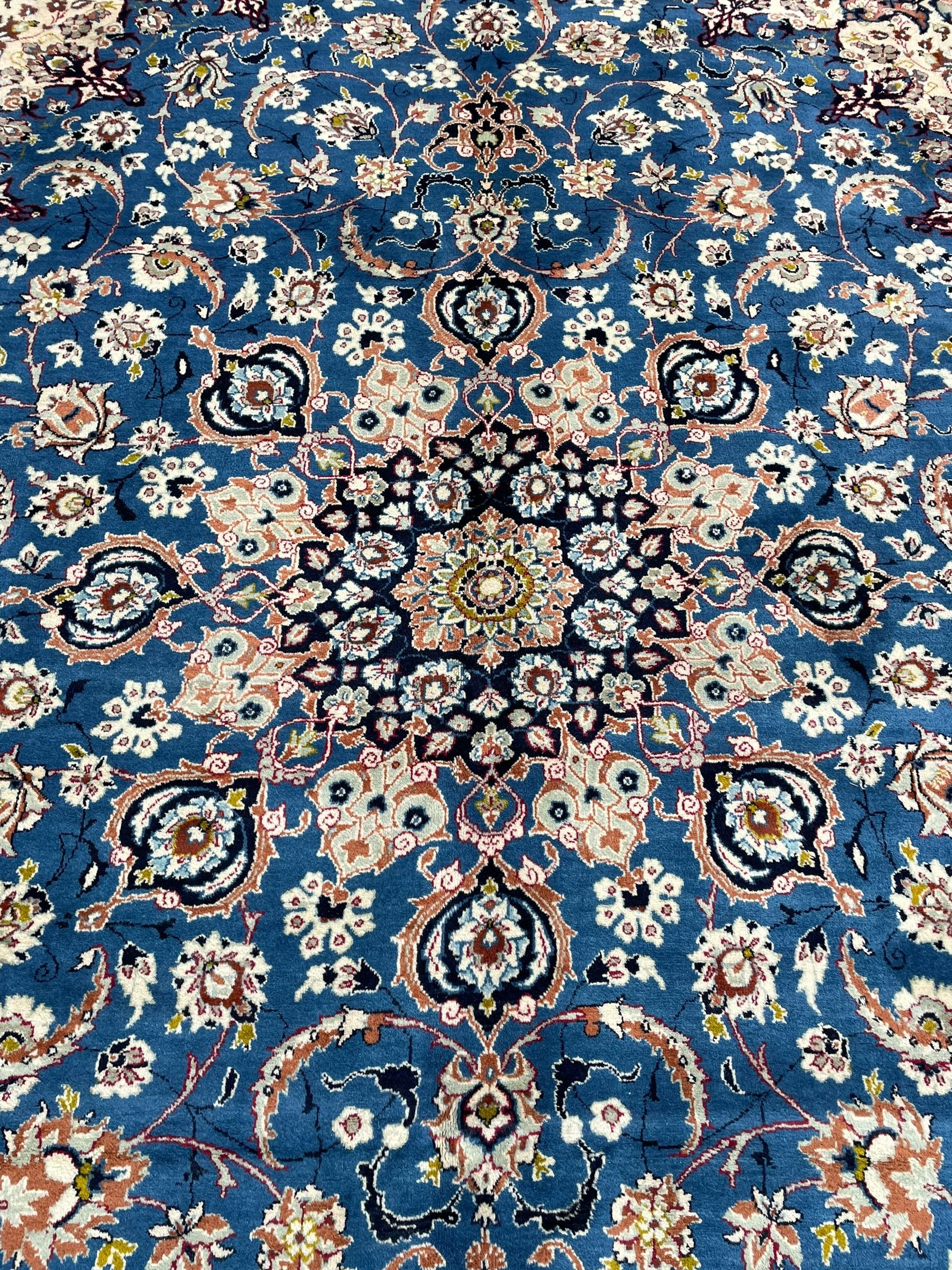 Persian Nain blue ground carpet, overall arabesque design, centre rosette medallion with eight projecting palmettes, the surrounding field decorated with interlacing branches and stylised plant motifs, within floral pale ground spandrels, the guarded border decorated with repeating stylised floral pattern 